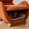 A cat is resting inside a unique, orange armchair that has a built-in cat bed. Náhled obrázku produktu