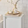 A bathroom cabinet with decorative items on top, including a reed diffuser, a candle, and a vase with branches, set against a tiled wall. Produktbild-Vorschau
