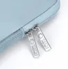 Close-up of two zipper pulls on a light blue laptop bag. Produktbild-Vorschau