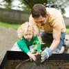 A father and daughter are planting a small plant in a garden bed. Voir les images du produit