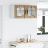 A wall-mounted kitchen cabinet with two doors, featuring a wood-grain finish on the doors and a white body, is shown against a white wall. Below the cabinet, a countertop with a bowl, a pitcher, and a mug is visible. Náhľad obrázku produktu