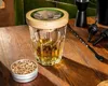 A whiskey glass with a smoking lid and a tin of wood chips on a wooden table. Voir les images du produit