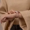 A close-up shot of a person's wrist wearing a rose gold metal watch strap. Produktbild-Vorschau