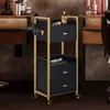 A black and gold rolling cart with drawers and a hairdryer holder, placed in a salon or barbershop setting. Produktbild-Vorschau