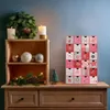 A Christmas-themed display on a wooden dresser, featuring an advent calendar, candles, a wreath, and decorative ornaments. Náhled obrázku produktu