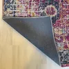 The underside of a rug is shown, with the patterned top visible at the top right. The rug is on a light-colored wooden floor. Produktbild-Vorschau