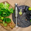 A hand blender set with accessories, surrounded by fresh ingredients like lettuce, cucumber, and kiwi, on a wooden and dark textured background. Anteprima dell’immagine prodotto