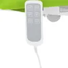 A close-up of a remote control for an electric massage table, attached to the table by a white cord. The table itself is visible in the background, with a bright green upholstered surface. Náhled obrázku produktu