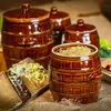 Several ceramic fermentation crocks are arranged on a burlap cloth, with some shredded cabbage visible on a wooden board in the foreground. Podgląd zdjęcia produktu