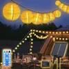 A campsite at night with string lights illuminating a tent and table. Voir les images du produit