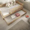 A wooden children's bed with a pull-out drawer containing folded clothes. Produktbild-Vorschau