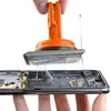 A hand is using an orange suction cup tool to lift a component from an electronic device. Produktbild-Vorschau
