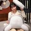 Junge Frau hält ein graues ergonomisches Rückenstützkissen mit weißem strukturiertem Mittelteil und ein passendes Bolsterkissen Náhled obrázku produktu