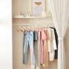 A closet with clothing hanging on a rack and decorative items on a shelf above. Produktbild-Vorschau
