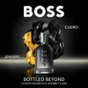 A bottle of BOSS BOTTLED BEYOND fragrance is displayed prominently against a dark, reflective background. Abstract elements of black leather and gold material are artfully arranged behind the bottle, suggesting the scent's notes. Podgląd zdjęcia produktu