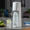 A white SodaStream soda maker is shown on a kitchen counter next to a glass of sparkling water with lime. Produktbild-Vorschau