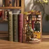A miniature diorama of a study room, resembling a book nook, is placed next to three decorative books. Náhled obrázku produktu