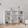 Three white bookshelves are arranged side-by-side against a textured concrete wall, with a wooden floor and a rug in the foreground. The shelves are decorated with various items like books, vases, and decorative objects. Produktbild-Vorschau