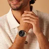 A man wearing a cream-colored knitted shirt and a silver watch on his left wrist, with his hands clasped in front of him. Voir les images du produit