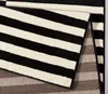 A close-up view of a black and white striped rug, folded to show the backing. Anteprima dell’immagine prodotto