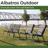 Four outdoor chairs with cushions are arranged on a grassy lawn in front of a bridge and city skyline. Produktbild-Vorschau