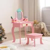 A child's pink vanity table and stool set with a strawberry theme, set up in a room with a Christmas tree and a basket of blankets. Produktbild-Vorschau