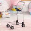 A toy shopping cart is shown in a child's room with a crib and storage baskets in the background. Produktbild-Vorschau
