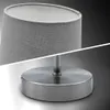 A close-up studio shot of a modern table lamp with a grey fabric shade and a brushed metal base and stem. Náhled obrázku produktu