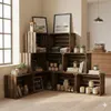 A corner display of wooden crates filled with various items, including folded clothes, candles, books, and plants, in a room with natural light and a brick wall in the background. Náhled obrázku produktu