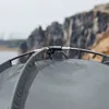 Close-up view of a tent's frame and fabric, with a rocky cliff and water in the background. Produktbild-Vorschau