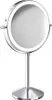 A silver, illuminated makeup mirror on a stand against a white background. Produktbild-Vorschau