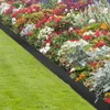 A garden bed with a black metal border separating it from a green lawn. Voir les images du produit