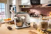 A kitchen counter with a stand mixer and various ingredients for baking. Anteprima dell’immagine prodotto