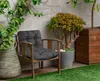 An outdoor chair with a cushion placed on it, next to plants and a wooden planter. Produktbild-Vorschau