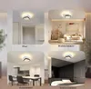 Collage of four images showing a modern black and white LED ceiling light installed in different rooms: a hallway, a living room, a dining room, and a bedroom. Produktbild-Vorschau