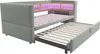 A light gray upholstered daybed with a pull-out trundle bed and built-in shelving illuminated by pink LED lights. Náhled obrázku produktu