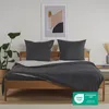 A bed with bedding and pillows, with a plant and artwork in the background. Voir les images du produit