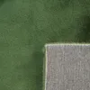 A close-up view of a green rug, showing the texture of the pile and the underside of the rug. Náhled obrázku produktu