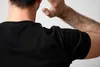 A person's back and shoulder are shown, with white flakes visible on their black t-shirt. Podgląd zdjęcia produktu