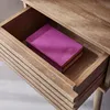 A close-up view of an open drawer in a wooden nightstand, revealing a purple notebook inside. Produktbild-Vorschau