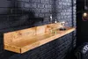 A wooden shelf mounted on a black brick wall, decorated with candles and a glass cloche. Produktbild-Vorschau