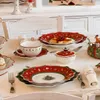 A Christmas-themed table setting with plates, cups, and decorations. Anteprima dell’immagine prodotto