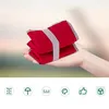 A hand holding folded red seat cushions with a grey strap, against a blurred background. Below are icons representing features. Produktbild-Vorschau