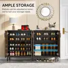 A shoe cabinet with its doors open, displaying shoes and boots on shelves. Decorative items and a lamp are on top of the cabinet. Voir les images du produit