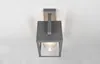 A modern gray outdoor wall lamp with a clear glass shade is mounted on a white wall. Anteprima dell’immagine prodotto