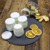 A collection of yogurt jars and dried fruit on a wooden table. Náhled obrázku produktu