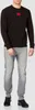 A man wearing a black Hugo Boss sweatshirt and gray jeans. Náhled obrázku produktu
