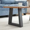 A close-up view of a coffee table with black metal legs and a wooden top, placed on a white rug in front of a blue sofa. Anteprima dell’immagine prodotto
