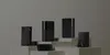 Several black electronic devices, likely networking equipment and a smartphone, are arranged on tiered white platforms against a plain gray background. Náhľad obrázku produktu