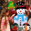 A young girl is decorating a felt snowman craft with various felt pieces. The background shows a Christmas tree and other festive decorations. Náhľad obrázku produktu